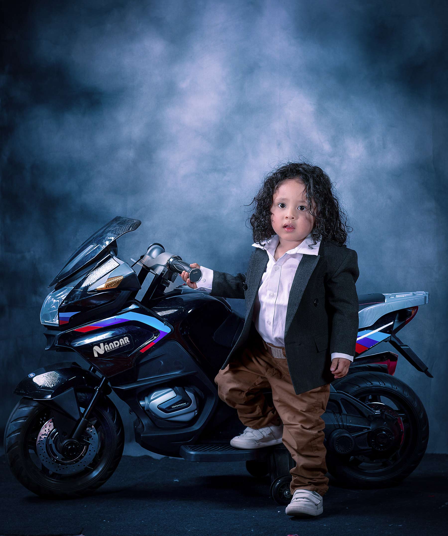 niño feliz con moto de juguete en sesion fotografica